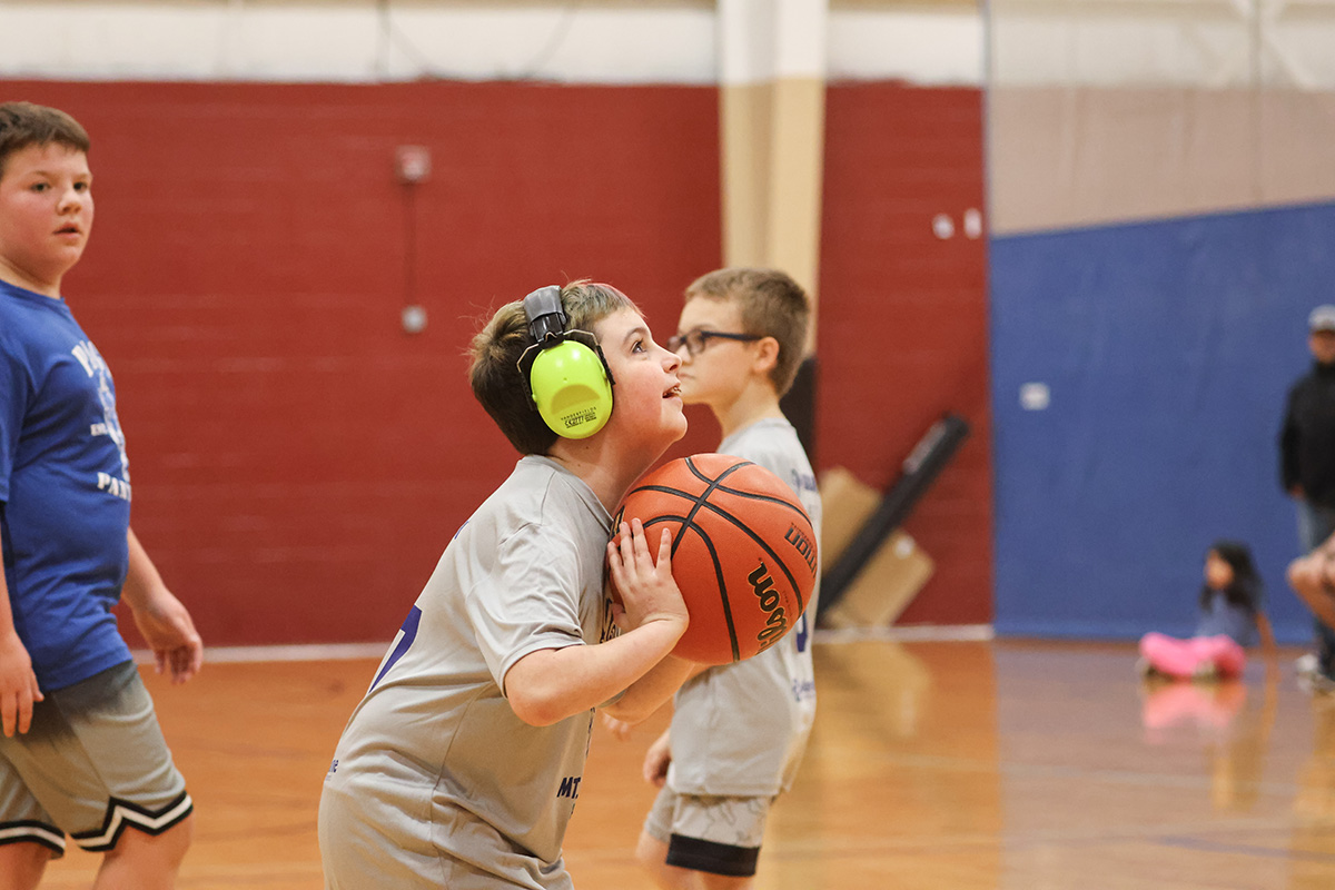 Child wearing headphones gets ready to shoot basketball