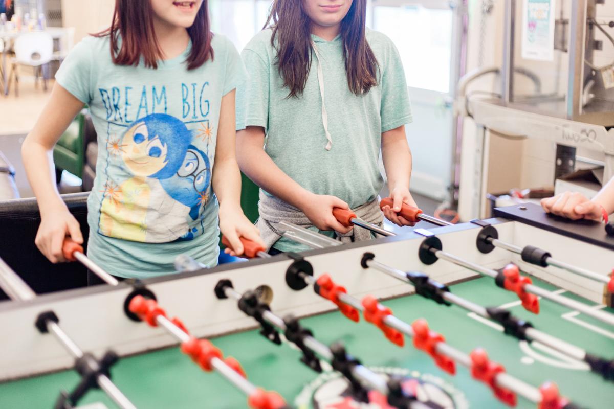 Two kids play foosball in the Two50 Youth Center