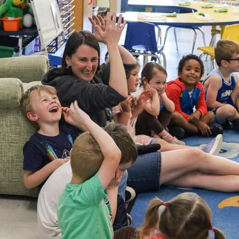Preschool teacher laughs with students during circle time