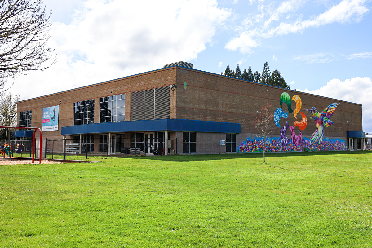 Exterior view of Willamalane Park Swim Center from park showing mural of a humming bird