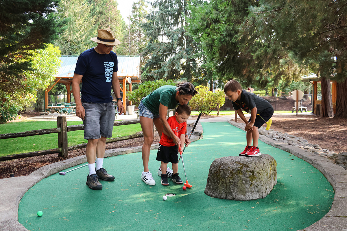 Family of four play minigolf