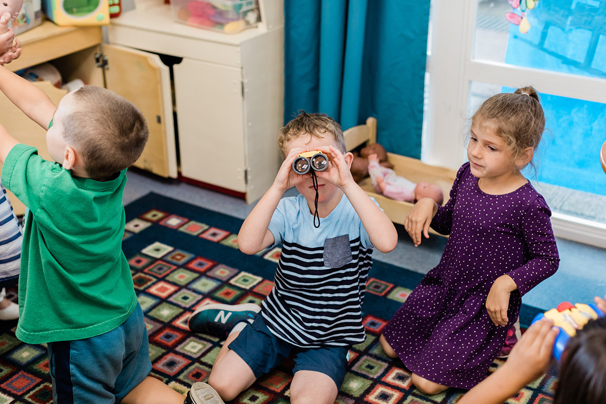 Three preschoolers play inside classroom