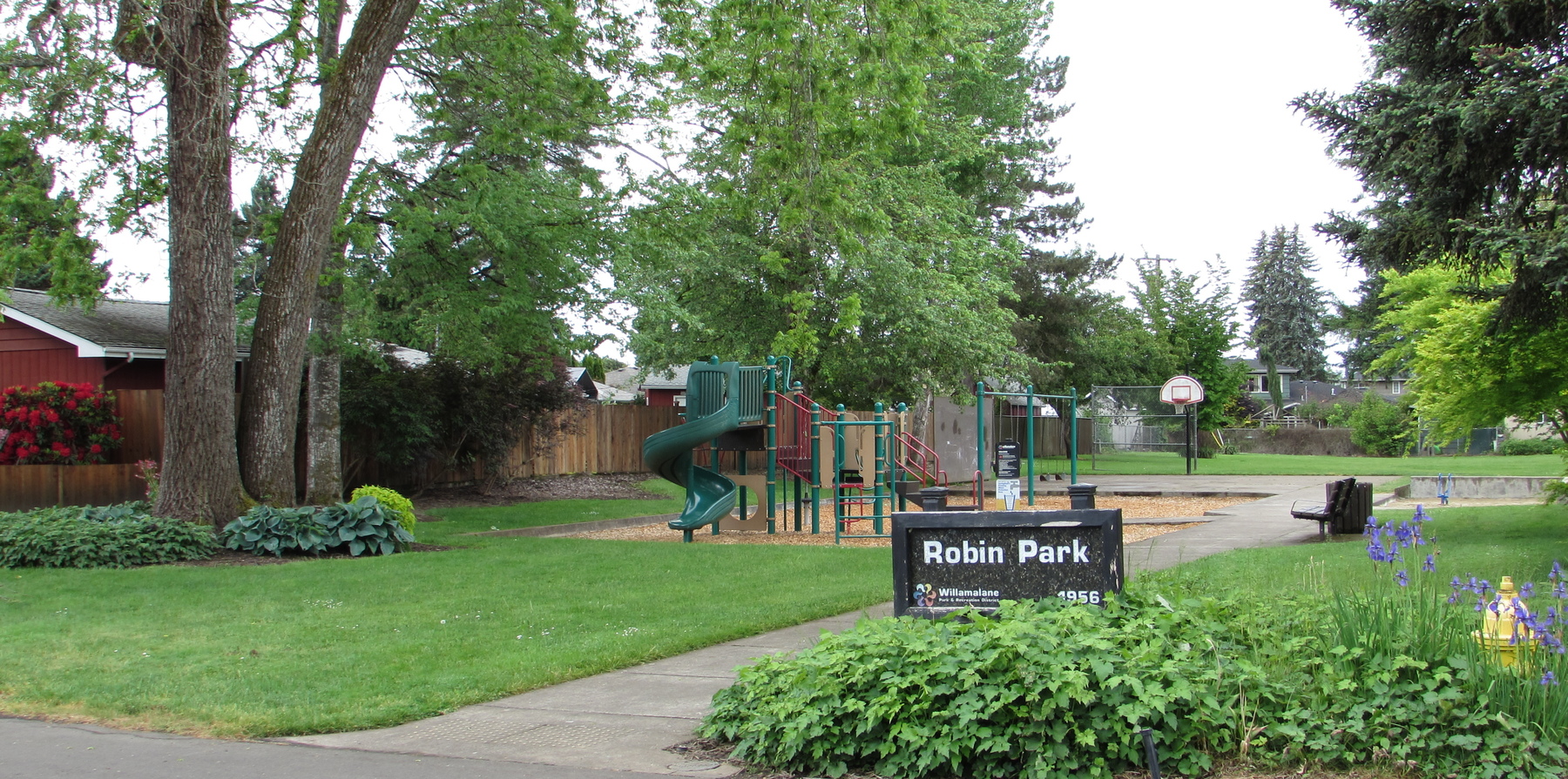 The entrance to Robin park shows a small playground and a paved path