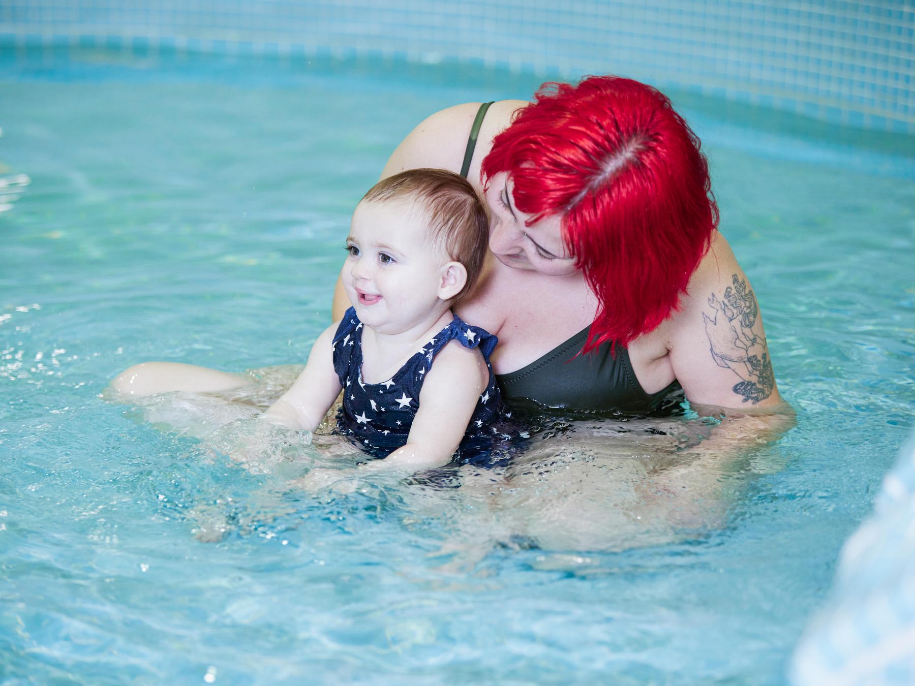 Parent and child play together in pool