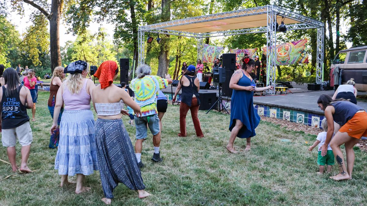 People dance at an outdoor concert in the grass