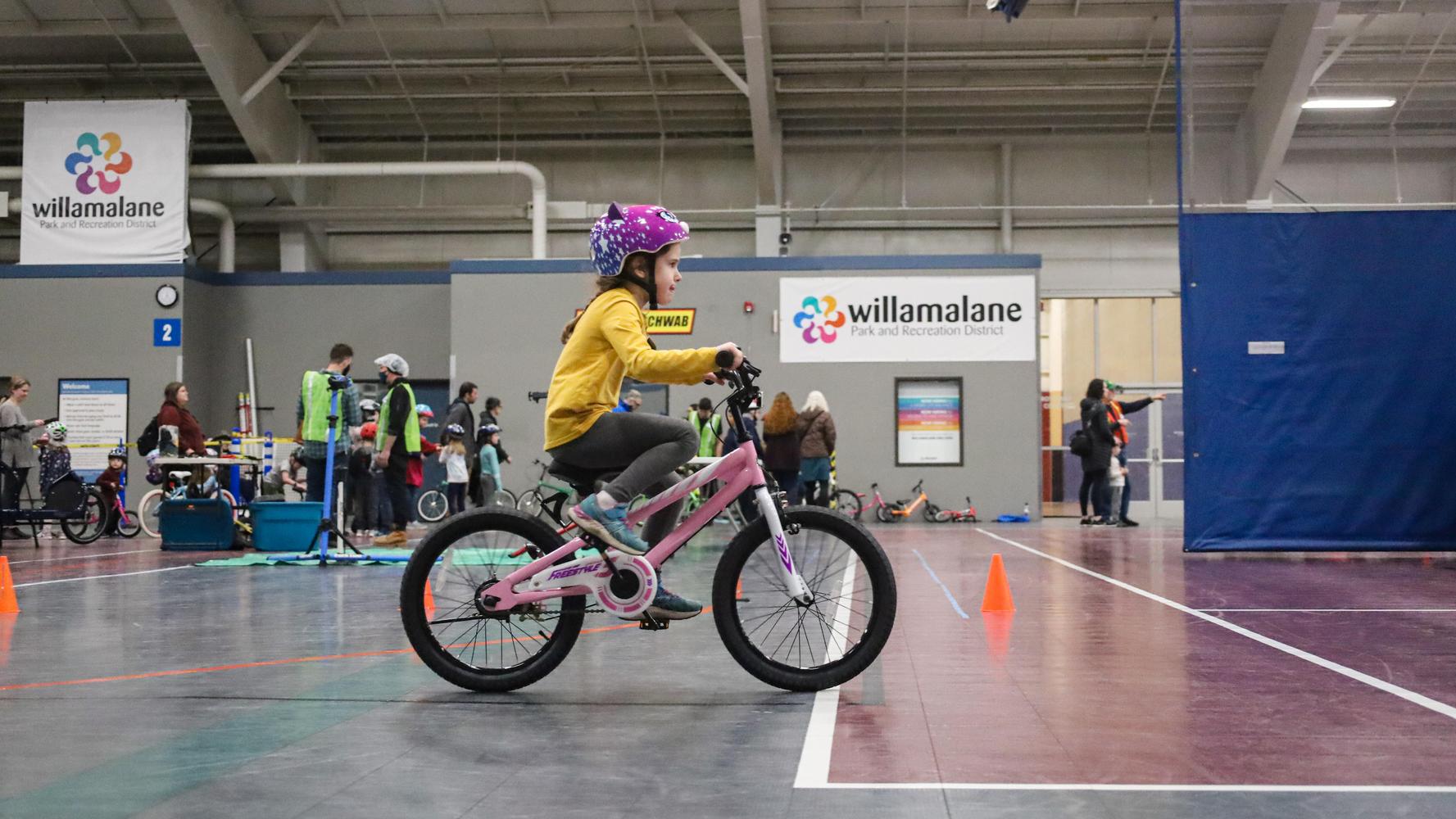 Child learns to ride a bike indoors at community event