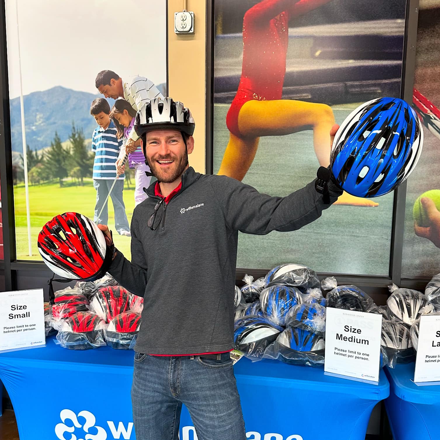 Willamalane staff member holds two helmets