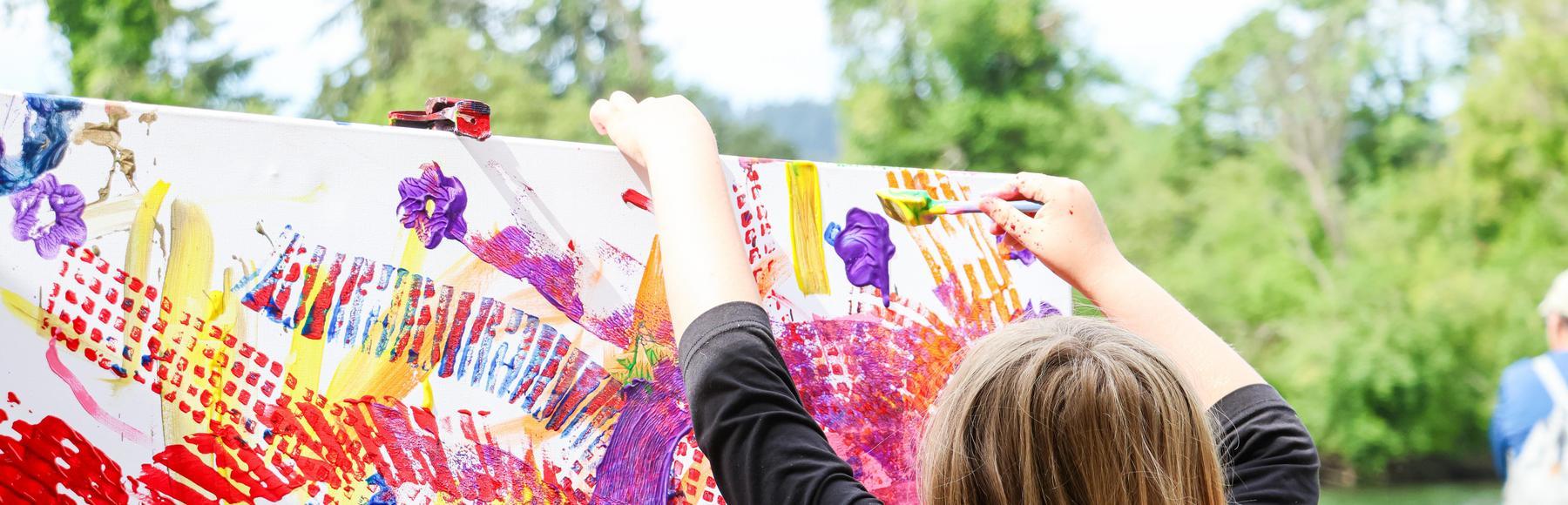 Child paints colorful community art outdoors