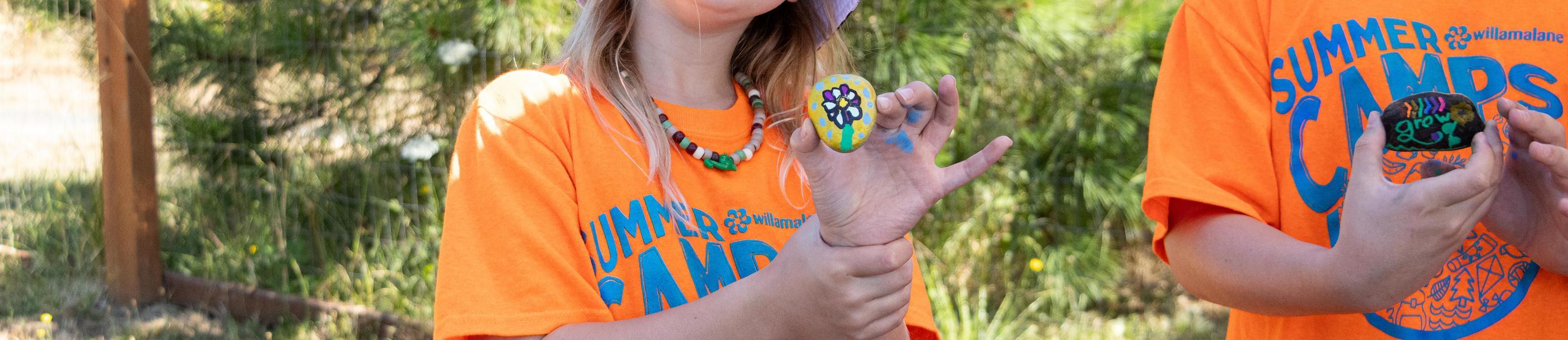 Two summer campers hold painted rocks
