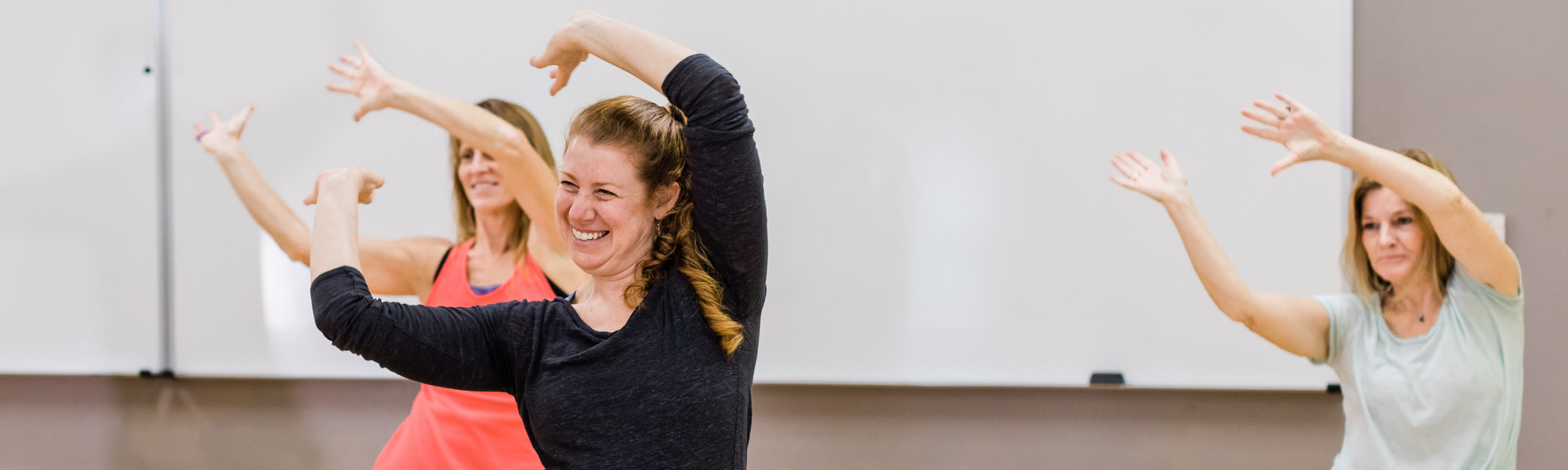 Three adults join smile and participate in an exercise class