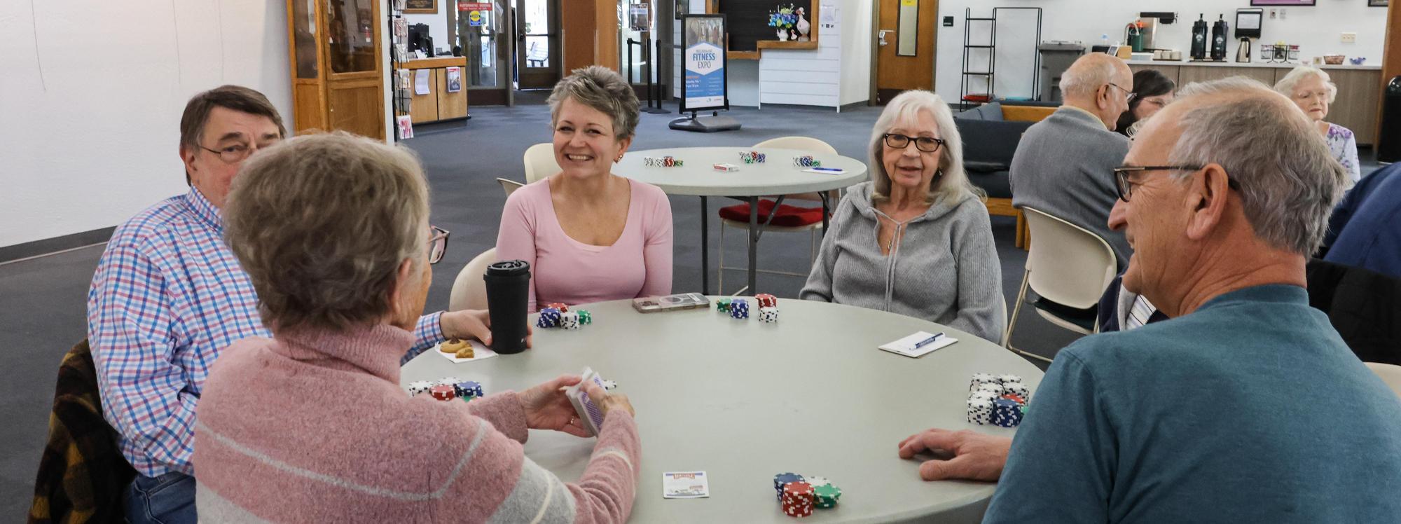 Group of people sit at a table and play cards
