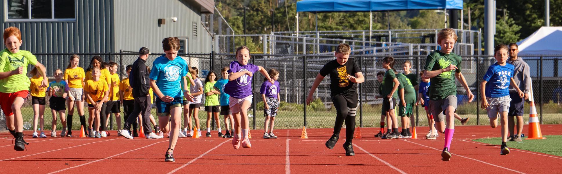 Kids run down track in elementary school meet