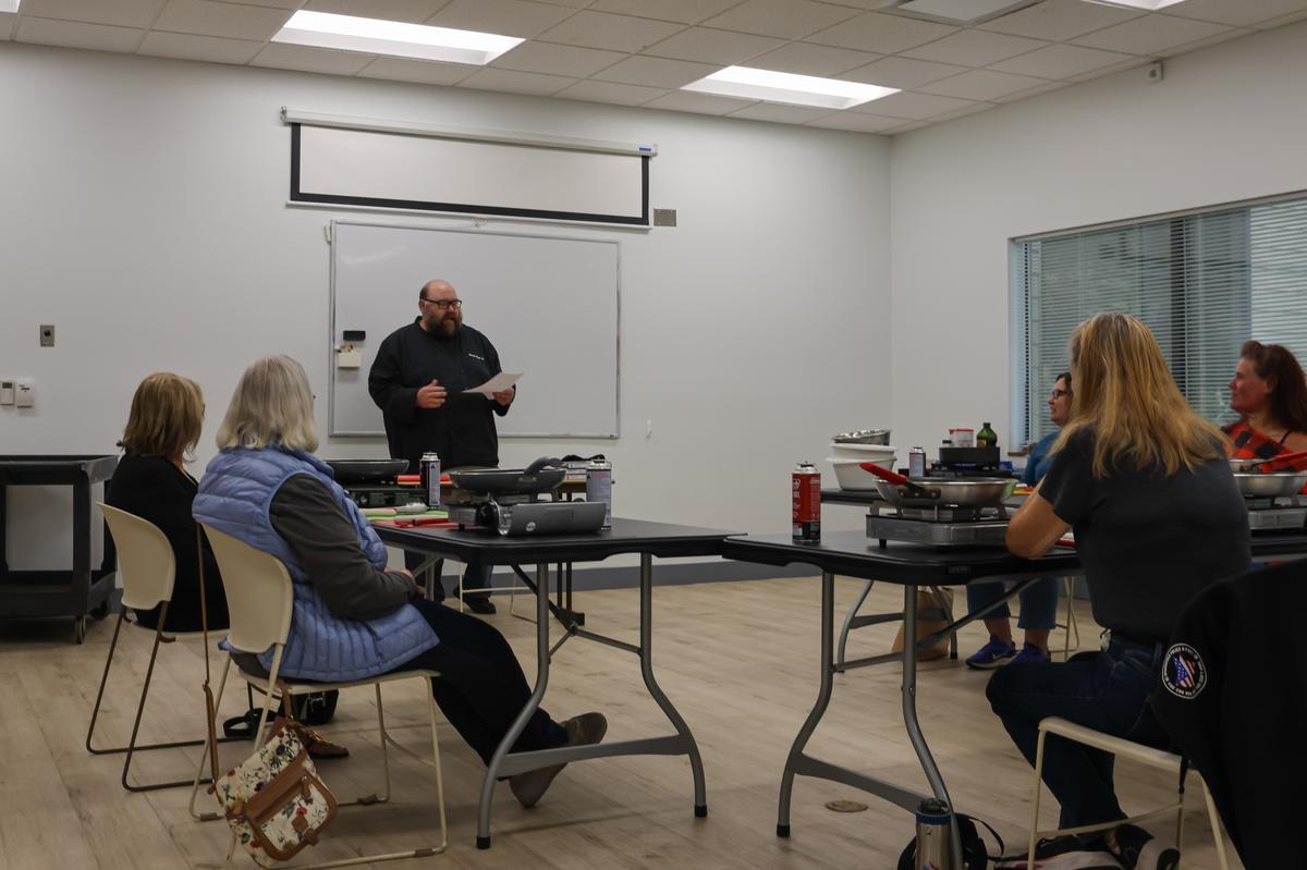 An adult stands at the front of the room, instructing a class of students.