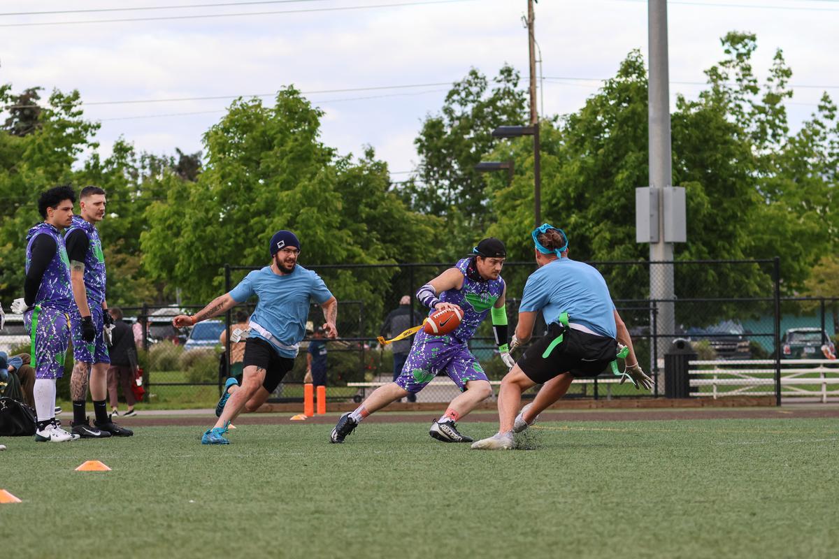 Two teams tossing a football on a green grass field.
