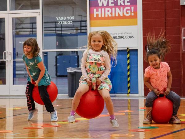 Preschools bounce on balls inside gym