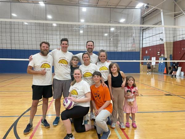 Six coed volleyball players pose with their family members in matching team shirts