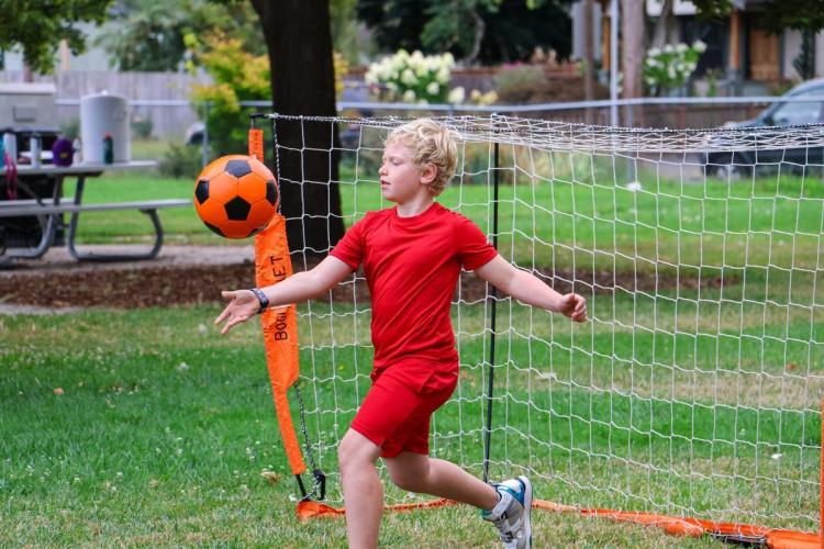 Young child in front of soccer goal playing with soccer ball.