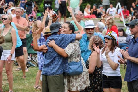 People hug and dance at an outdoor concert.