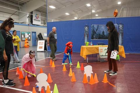 Two kids race along cones on a gym floor 