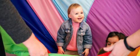 Toddler stands in the middle of parachute