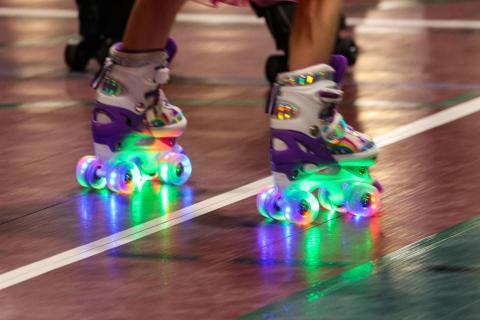 Two glowing rainbow skates roll on the floor.