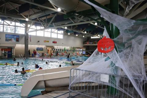 An orange pumpkin hangs above an indoor pool.