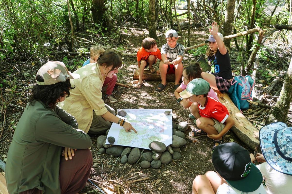 A group of campers sits in a circle looking at a map.
