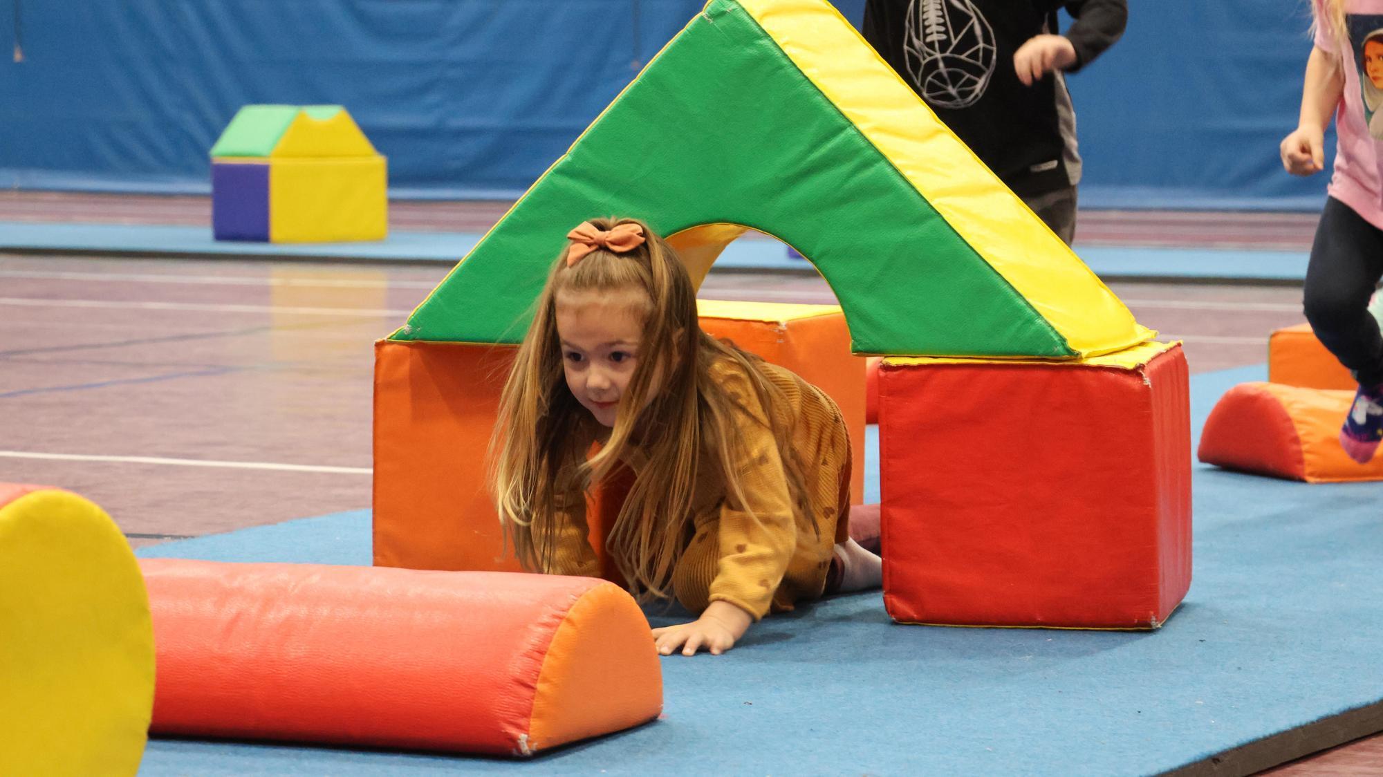 A preschooler crawls through obstacle course