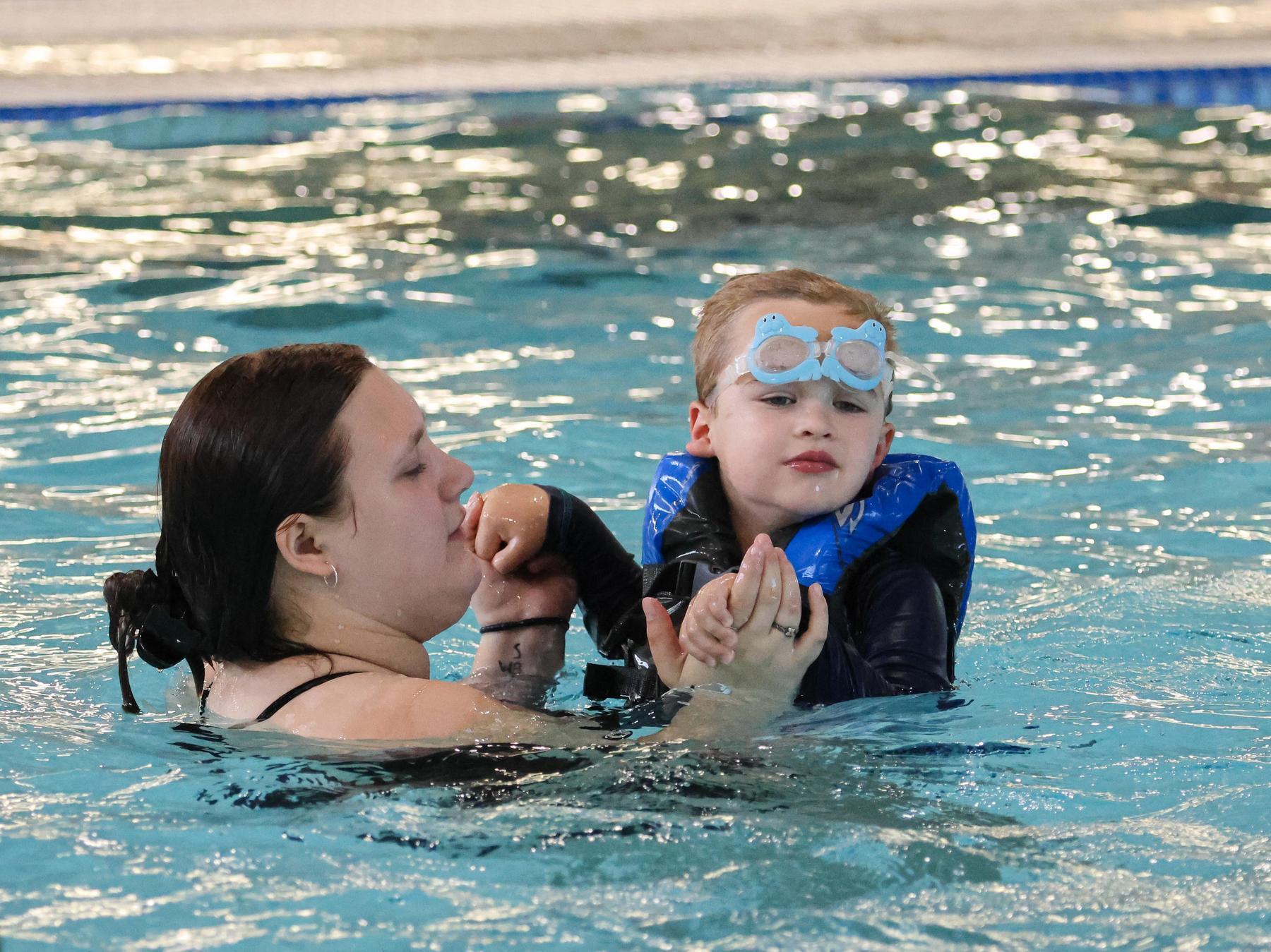 Teacher helps student swim in the water