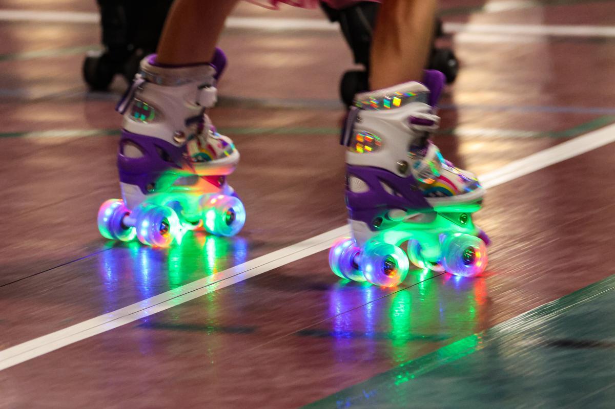 Two glowing rainbow skates roll on the floor.