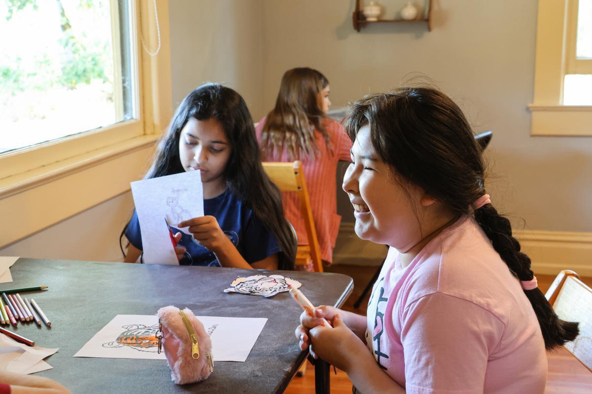 A child smiles while holding a marker and art project.