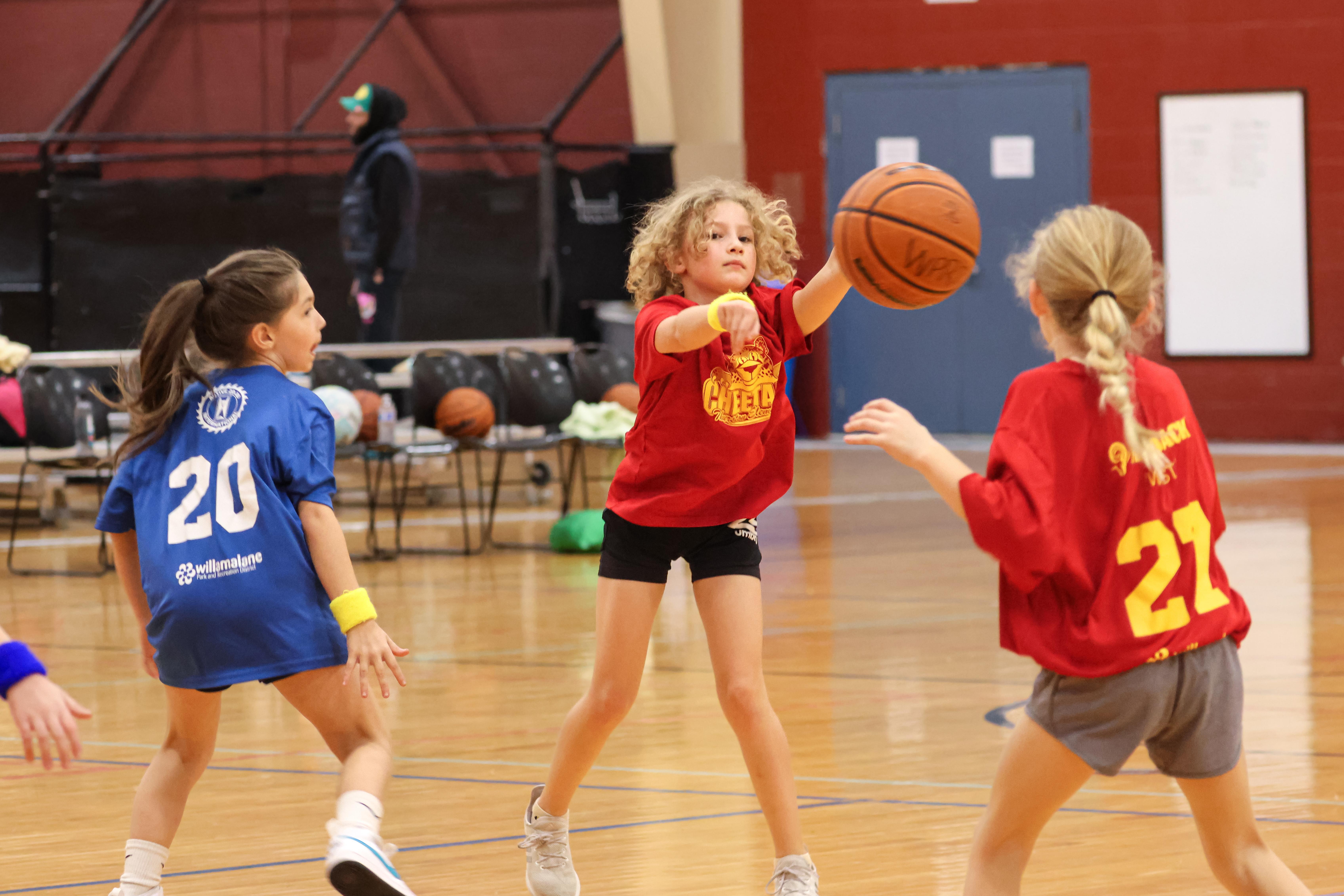 A player throws a basketball to her teammate on the court.
