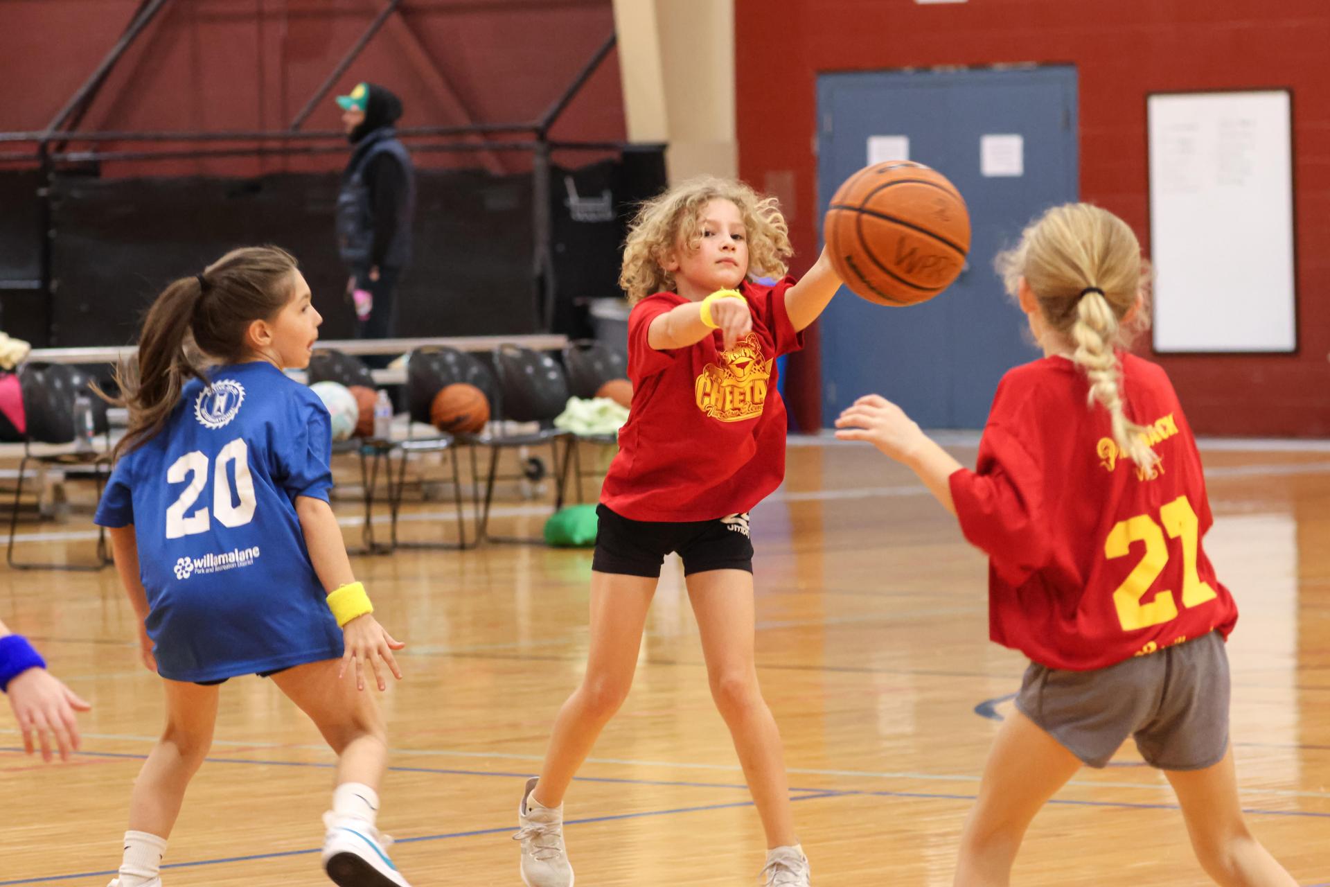 A player throws a basketball to her teammate on the court.