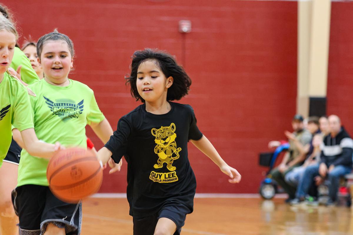 A young player dribbles a basketball on an indoor court.