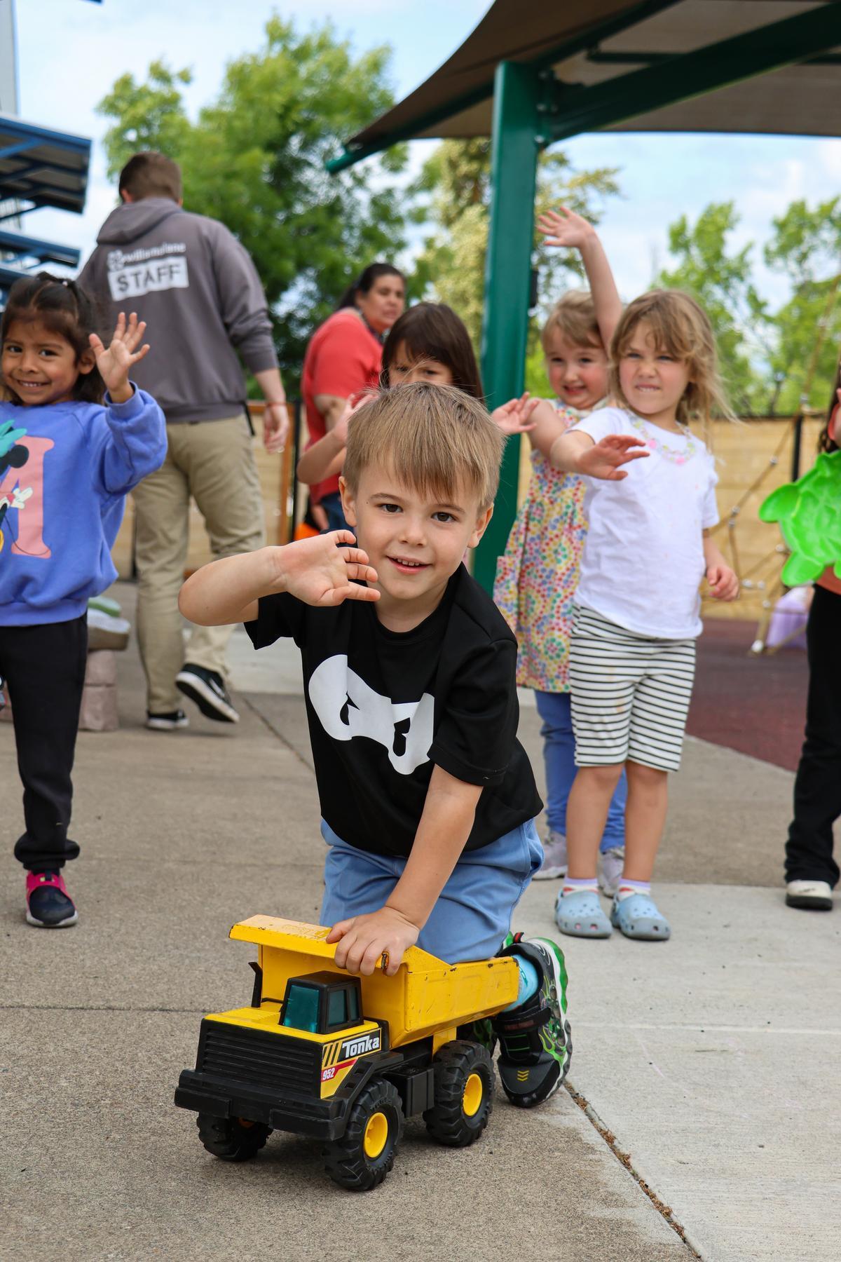 A child rolls a yellow toy truck.