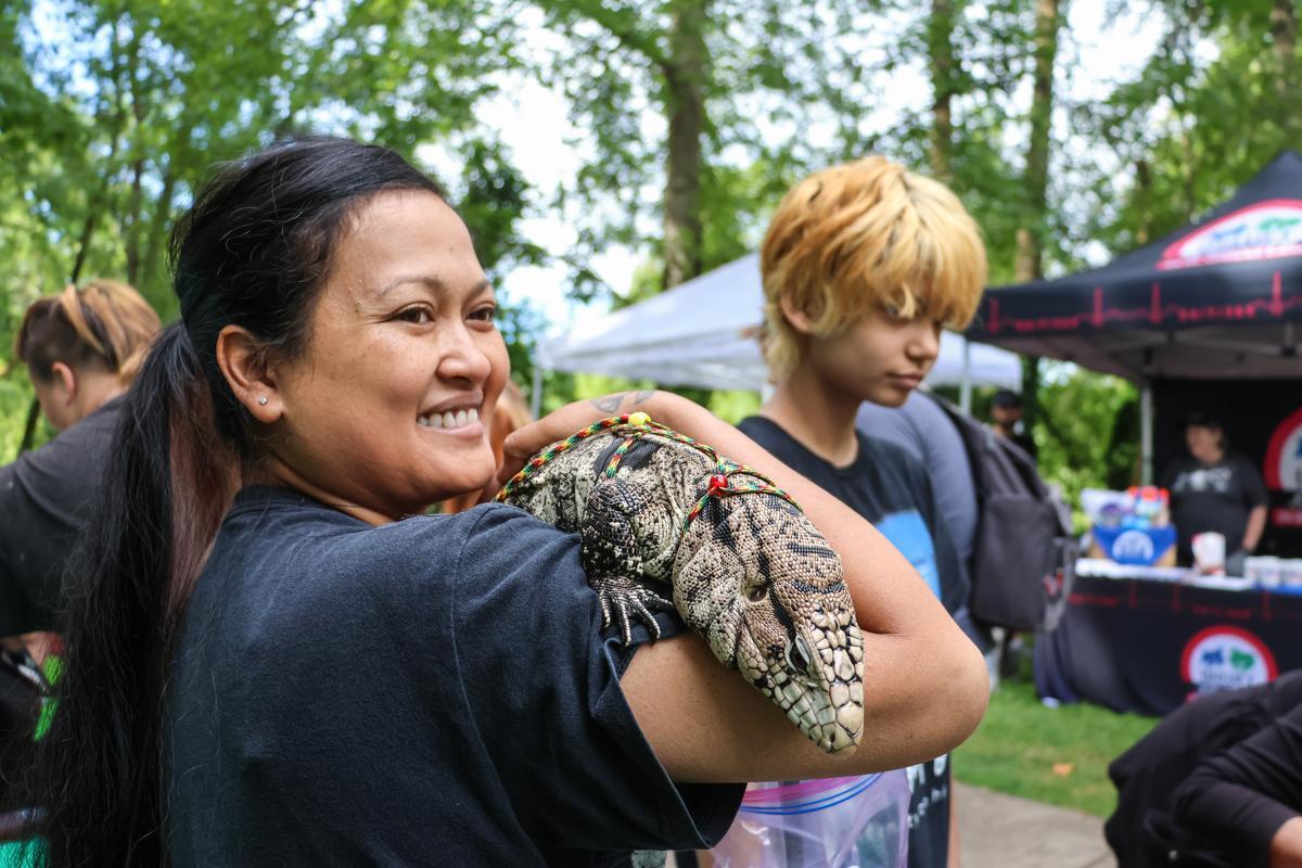 Vendor at Children's Celebration holds large lizard