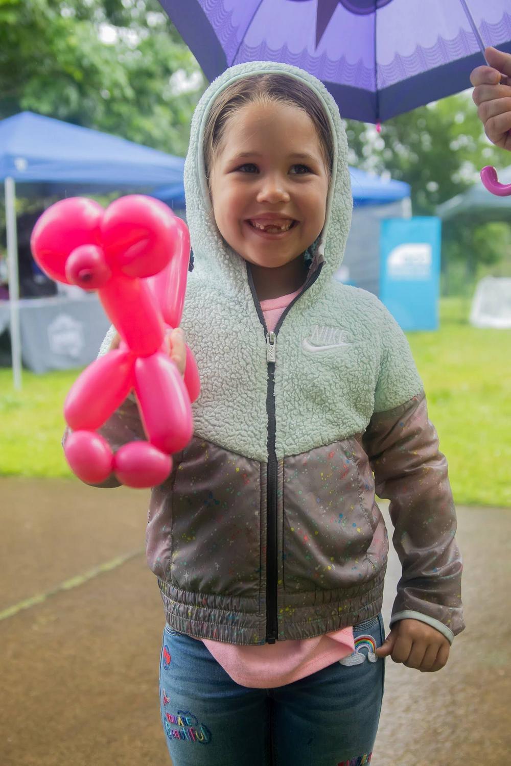 Child smiles with balloon animal at Children's Celebration