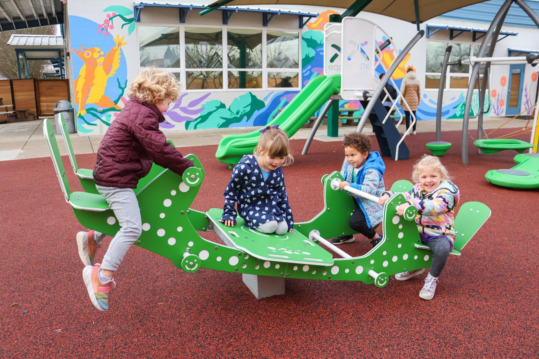 Kids play on outdoor play equipment at the Tiny Ducks playground