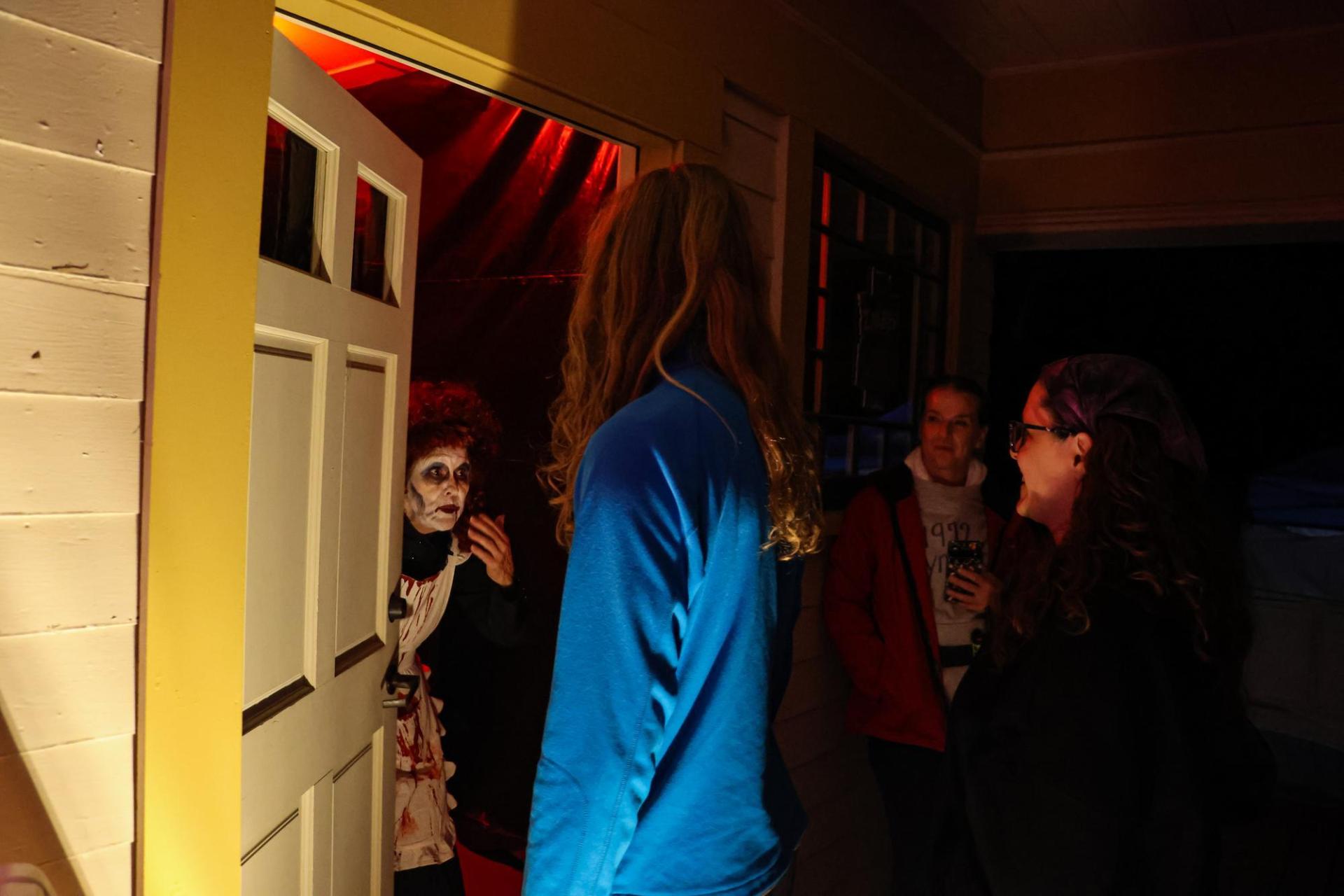 A costumed actor welcomes guests into the haunted house