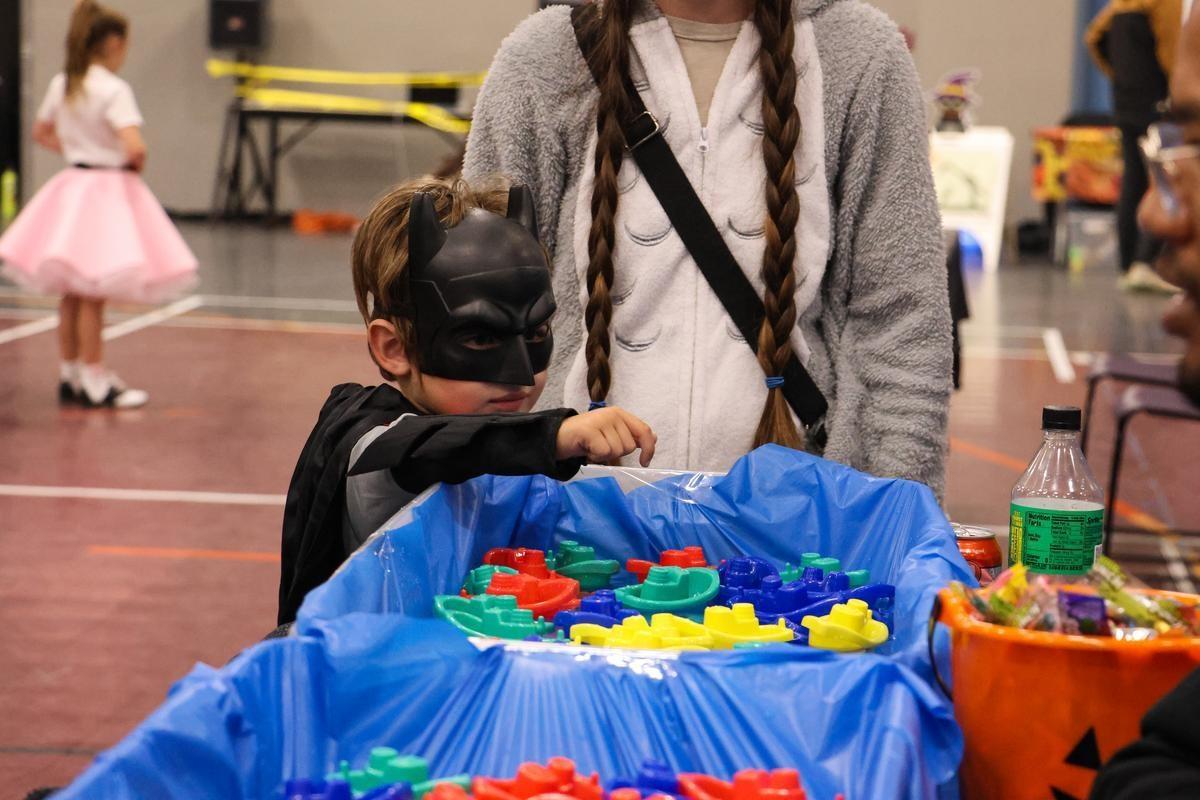 A child dressed like Batman reaches for a sensory toy.