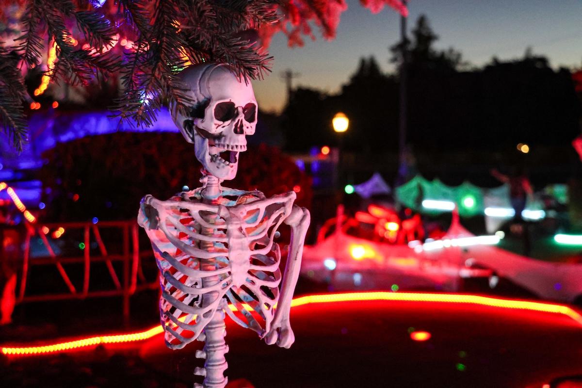 A skeleton decoration in front of colorful lights. 