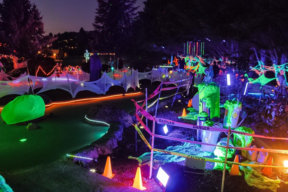 A mini golf course at night with colorful lights and decorations.