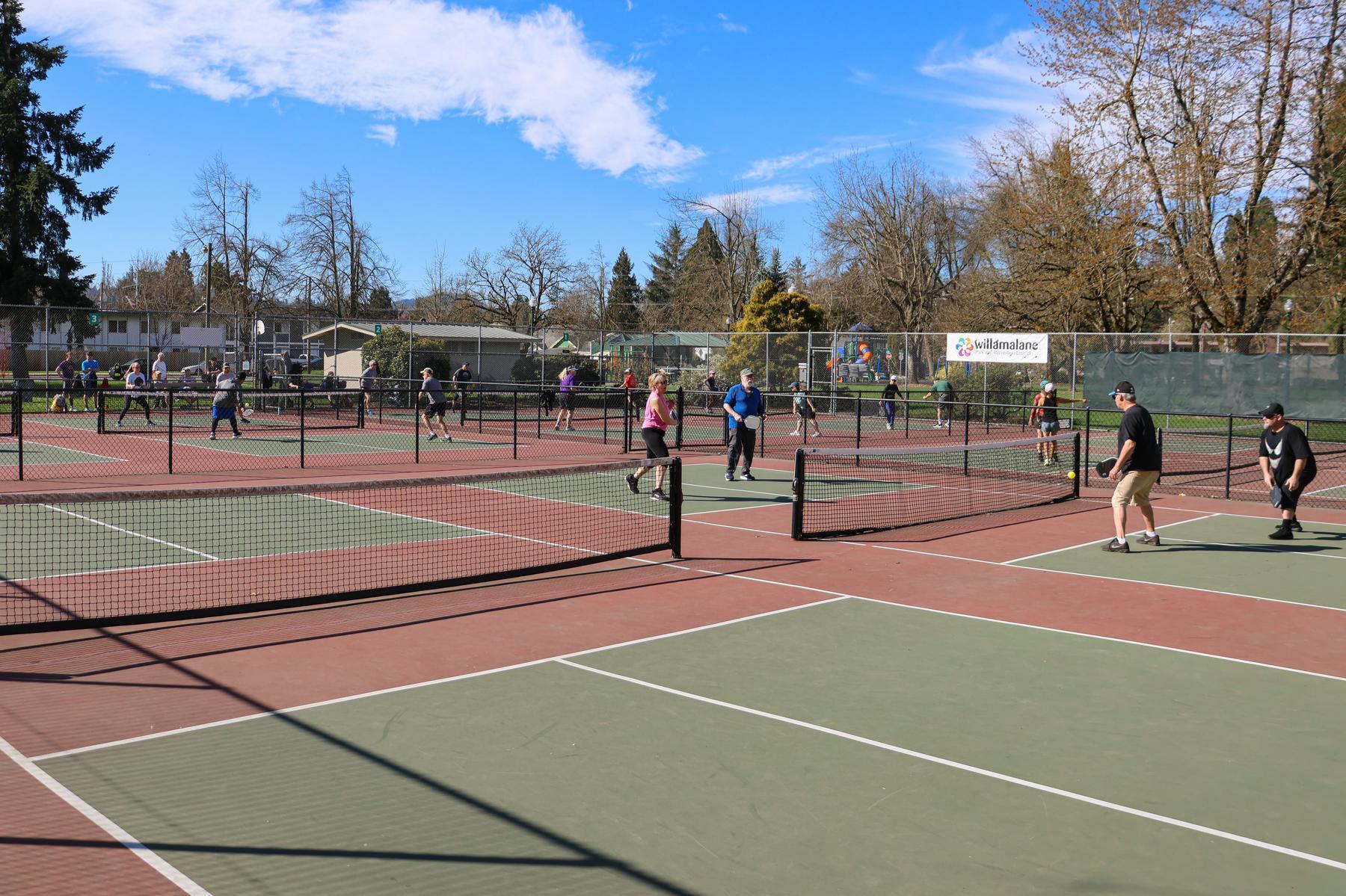 People play on outdoor pickleball courts at Meadow Park