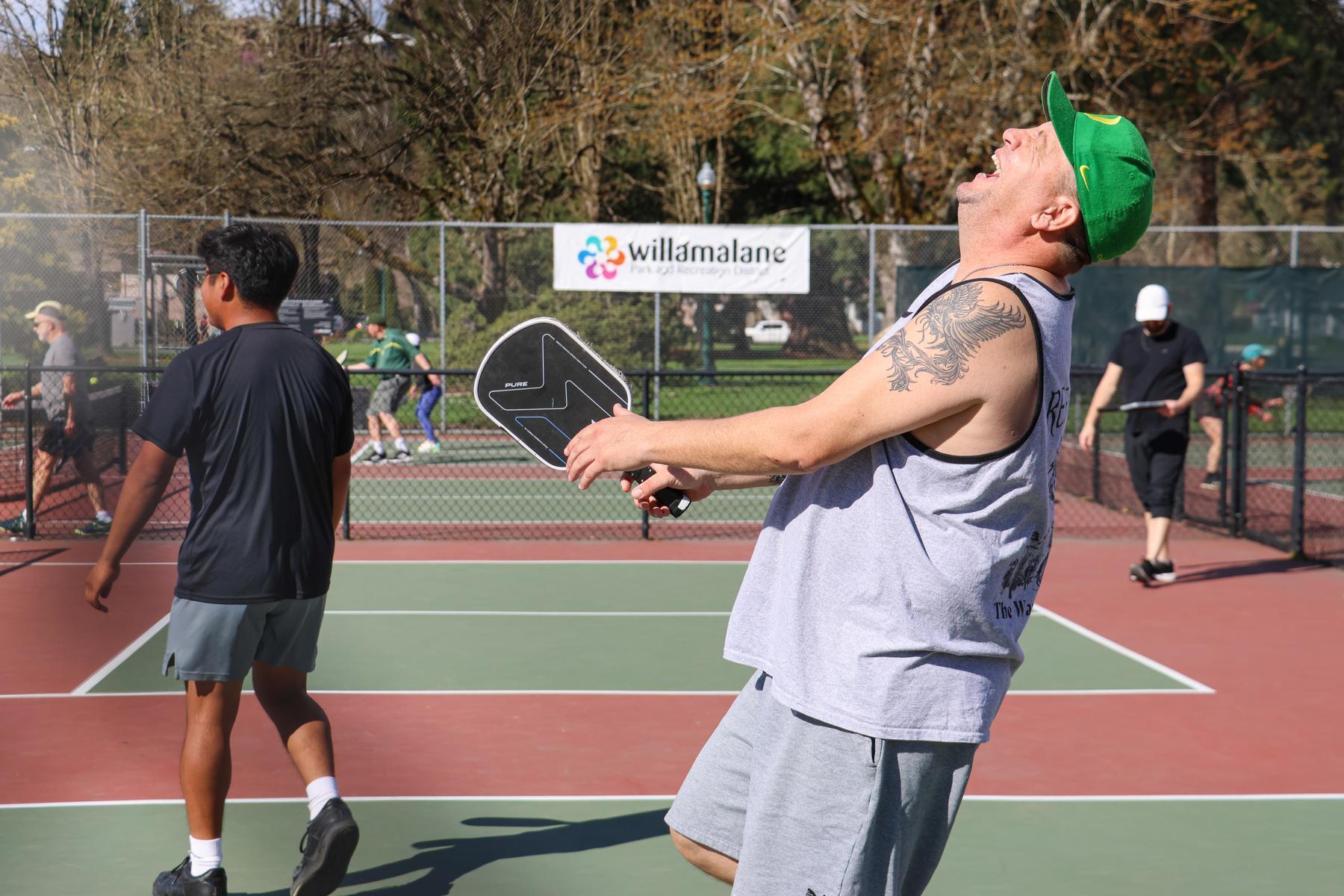 Person laughing while playing pickleball on outdoor courts at Meadow Park