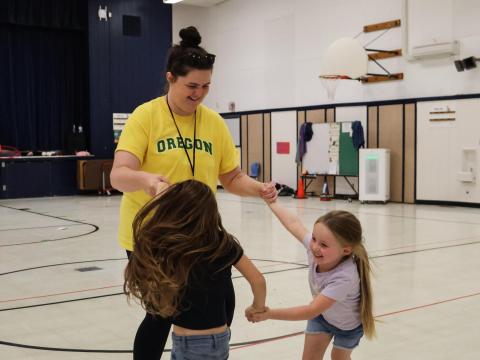 Willamalane staff member plays with students in gym